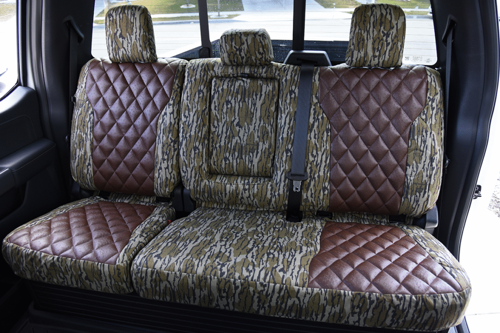 Rear seat view of 2026 Ford F-350 seat covers in Brown Ostrich Diamond Stitch leatherette and Mossy Oak Bottomland camouflage